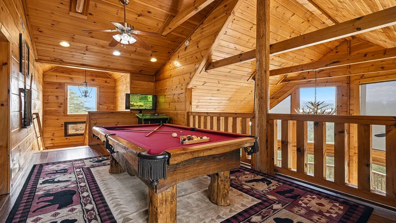 Game loft with red-felt pool table, mountain views through the railing